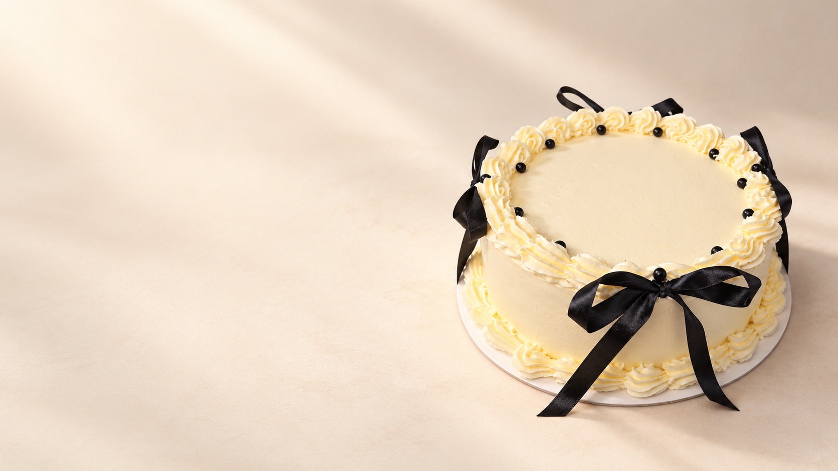 Helle Torte mit schwarzen Satinschleifen und dunklen Perlen